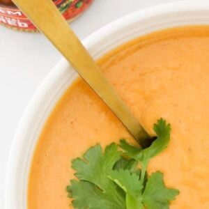 An overhead shot of a bowl of roasted Thai Pumpkin Soup with coriander on top.