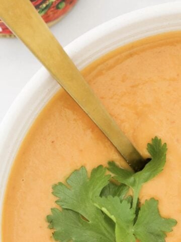 An overhead shot of a bowl of roasted Thai Pumpkin Soup with coriander on top.