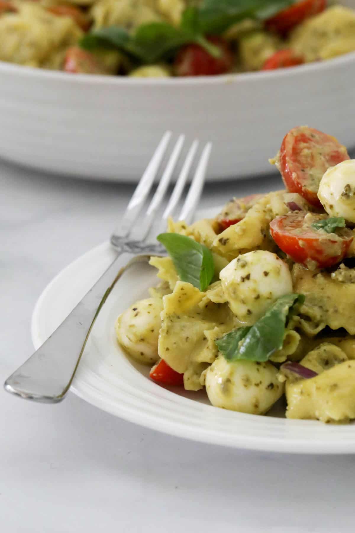 A white serving plate with tortellini pasta salad on it.