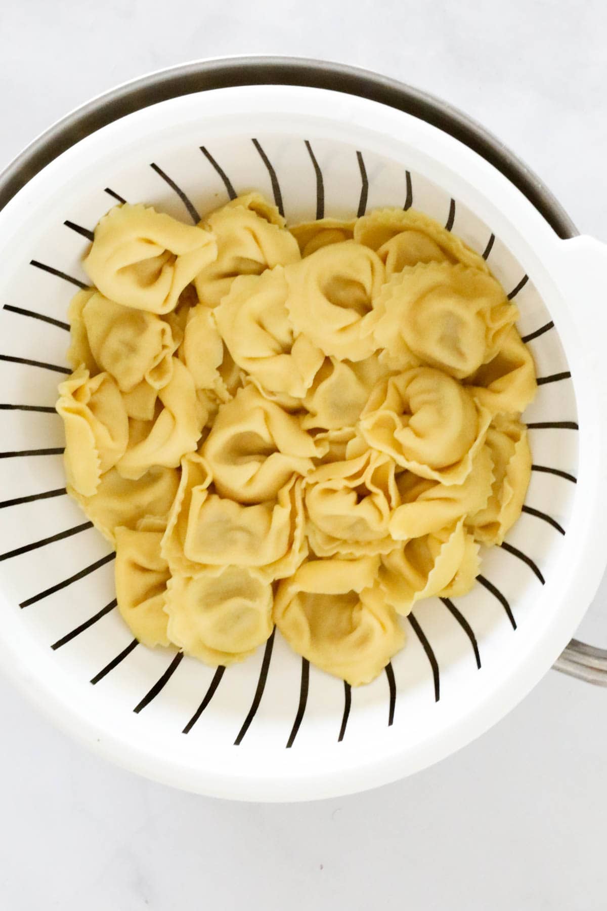 Cooked tortellini drained in a colander.