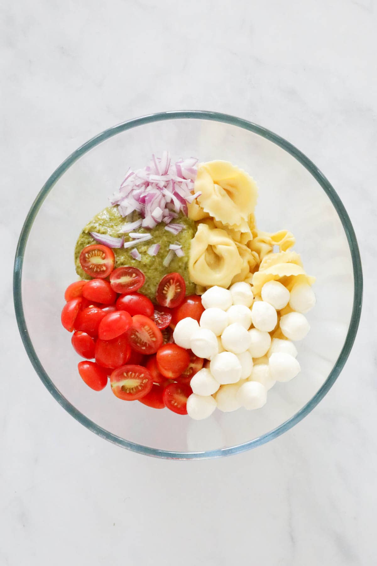 Chopped tomatoes, red onion, baby bocconcini, and pesto sauce added to cooked pasta.