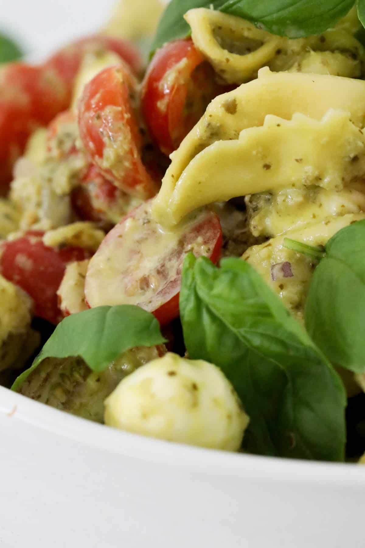 A close up of tortellini salad with pesto.