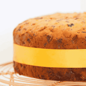 A fruit cake with a yellow ribbon tied around it.