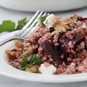 A plate of beetroot and quinoa salad with crumbled feta and mint leaves on top.