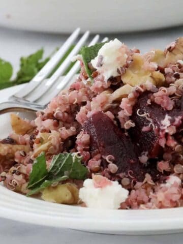 A plate of beetroot and quinoa salad with crumbled feta and mint leaves on top.