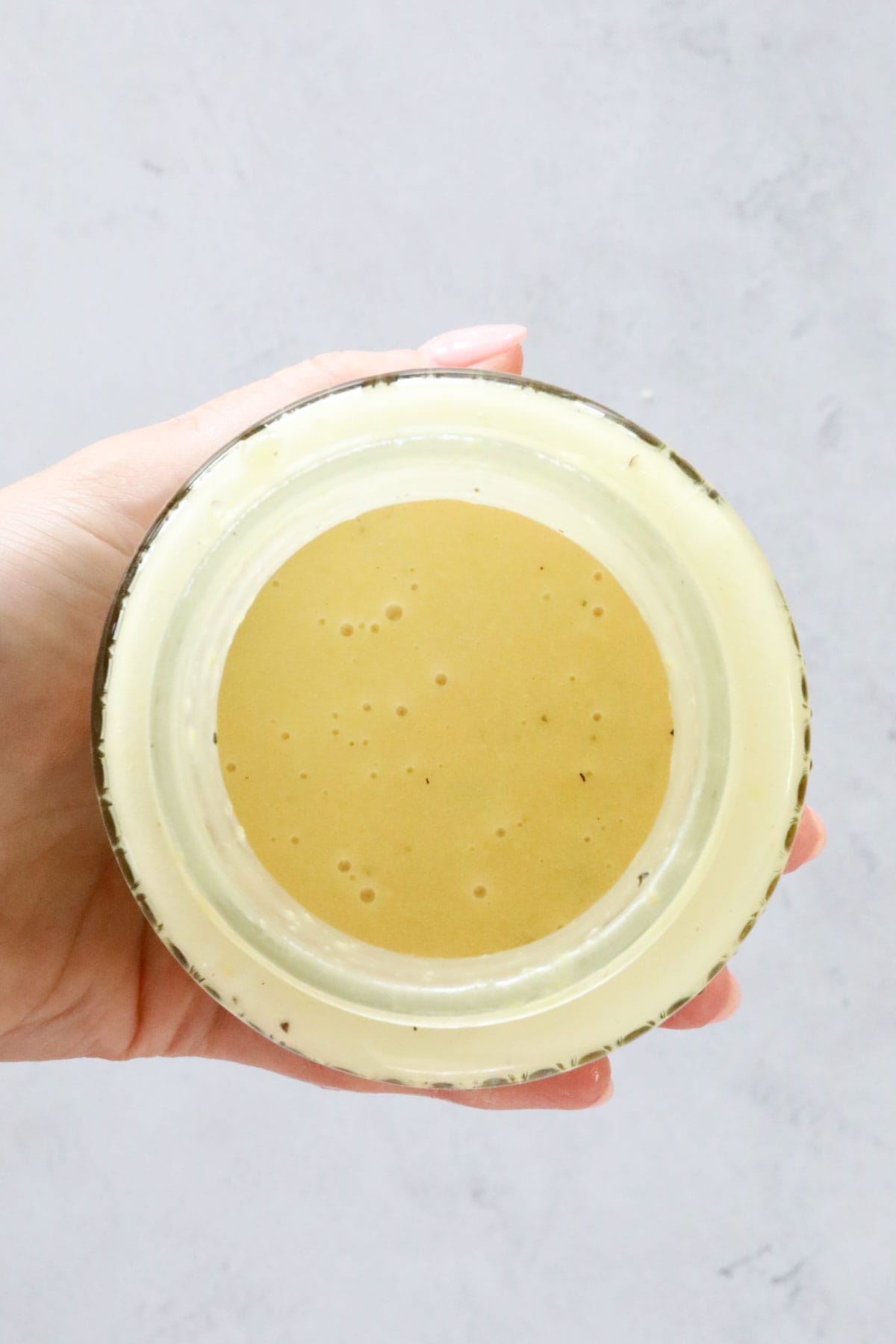 Honey mustard dressing being held in a small jar.