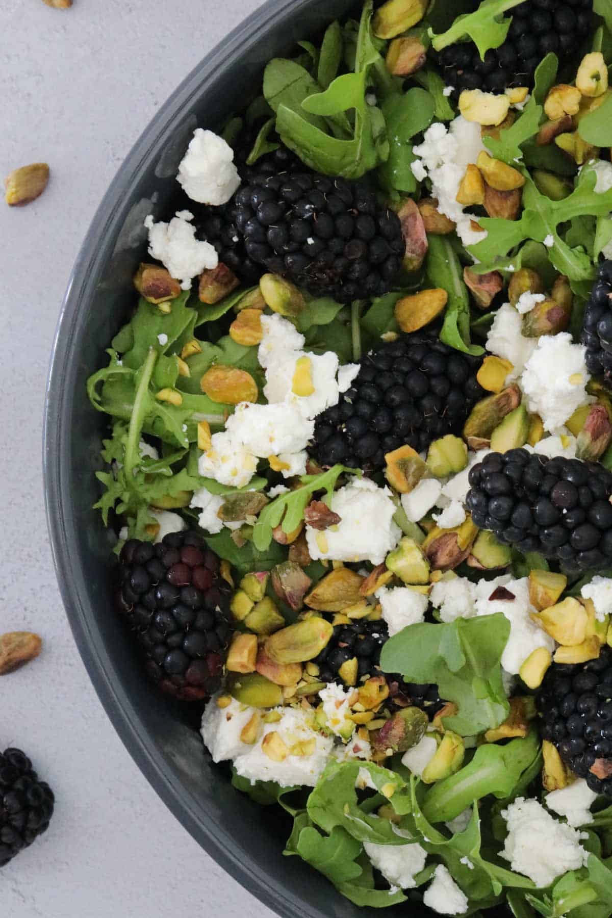 A close up showing fresh blackberries over rocket leaves.