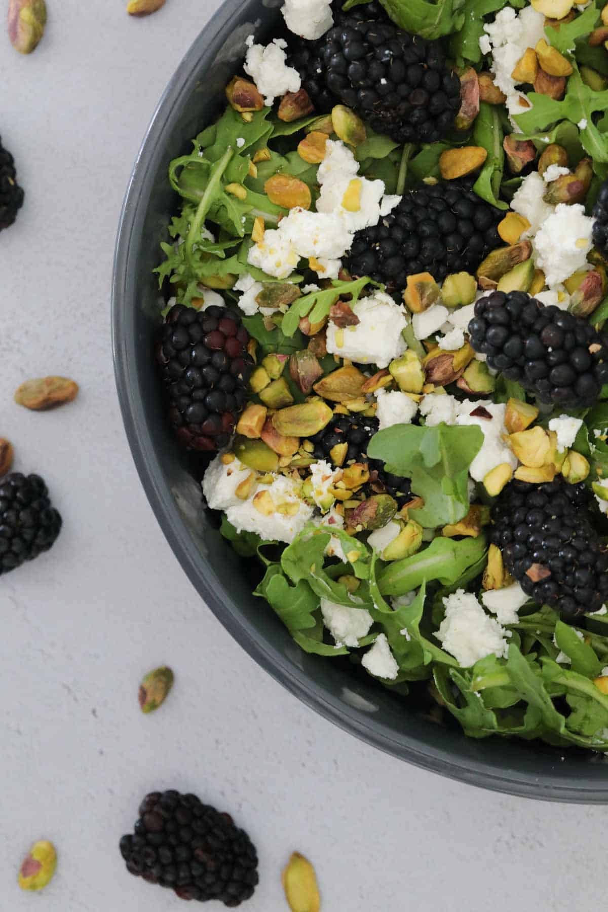 Crumbled feta, chopped pistachios, fresh blackberries, dressed in a honey mustard dressing and served in a black bowl.