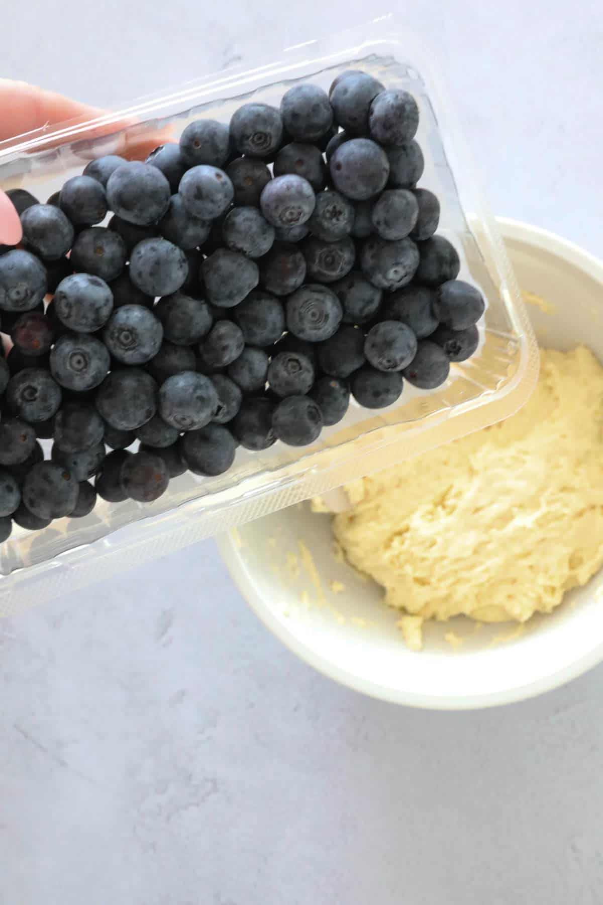 Fresh blueberries held above the muffin batter in a bowl.