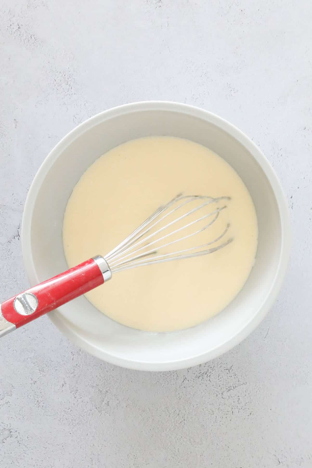 Vegetable oil, Greek yogurt, milk, eggs, and vanilla extract whisked in a bowl.