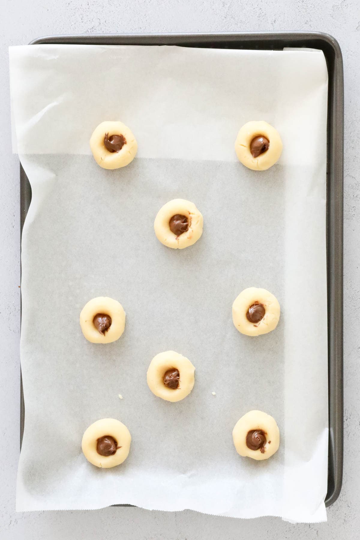 A small amount of Nutella spooned into the indent on each unbaked cookie.