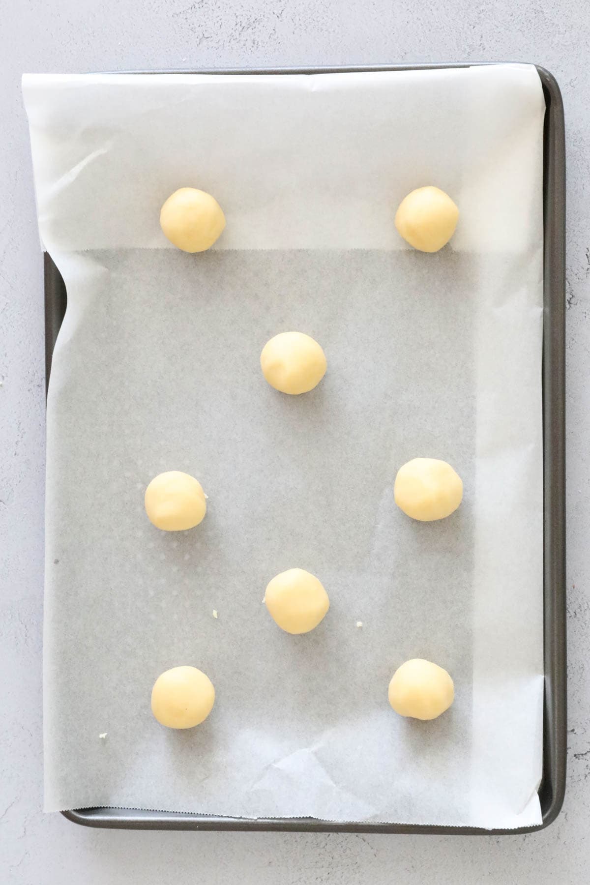 Cookie dough balls rolled out and placed on baking sheets.