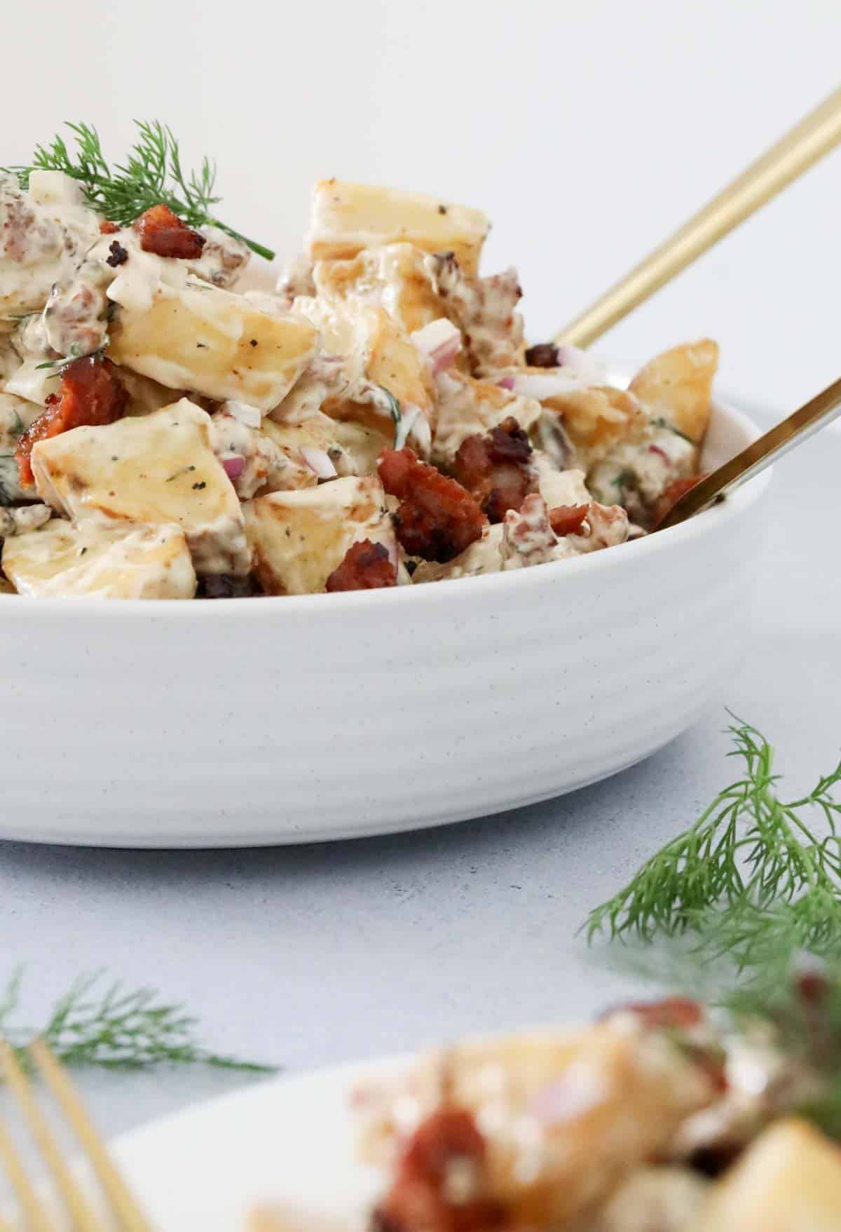 A white bowl filled with a creamy potato salad.