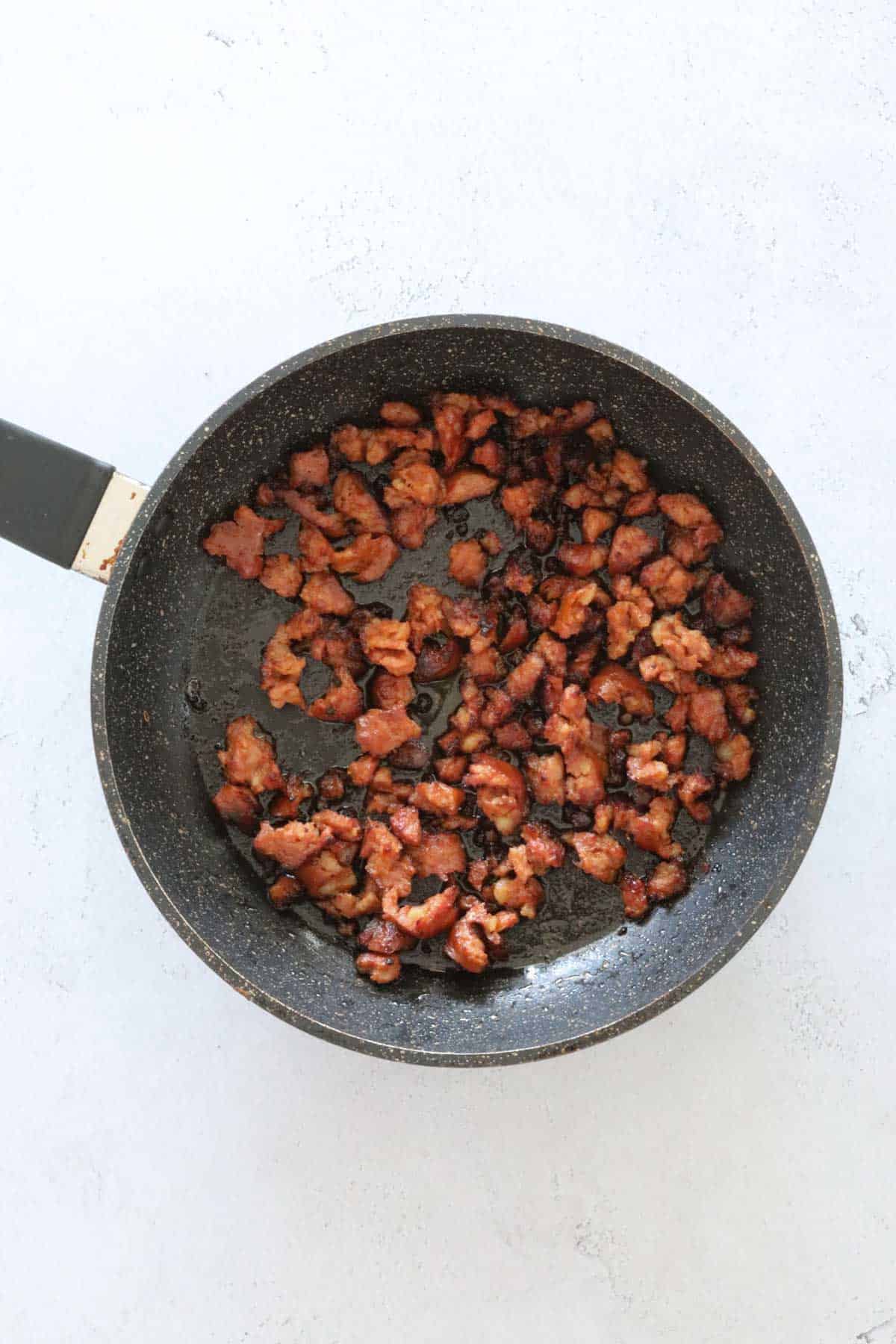 Crumbled chorizo fried in a shallow pan.