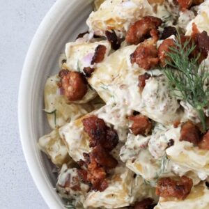 An overhead shot of a bowl filled with roasted potatoes, dill and fried chorizo in a creamy dressing.