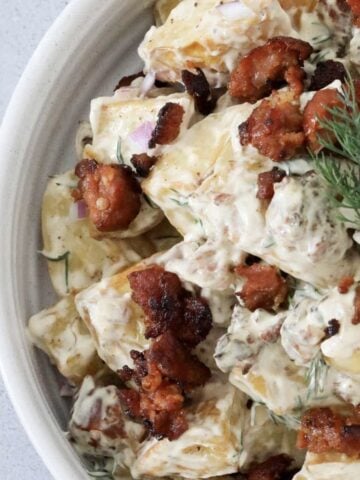 An overhead shot of a bowl filled with roasted potatoes, dill and fried chorizo in a creamy dressing.