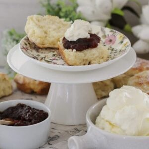 A cake stand topped with fluffy lemonade scones with whipped cream and jam.