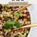 An overhead shot of bean salad with gold salad servers resting in the bowl.