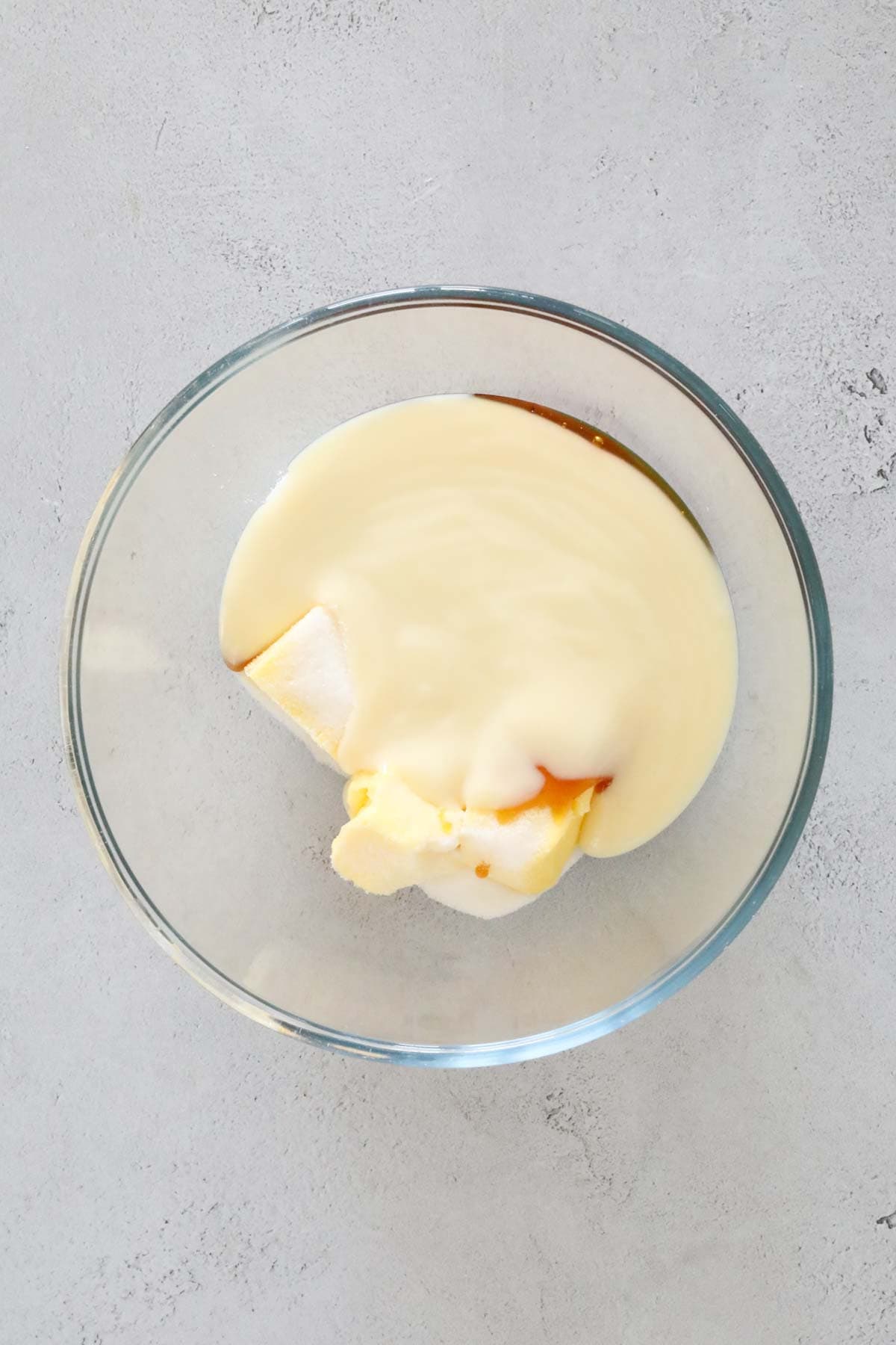 Condensed milk, sugar, butter and golden syrup in a glass bowl.