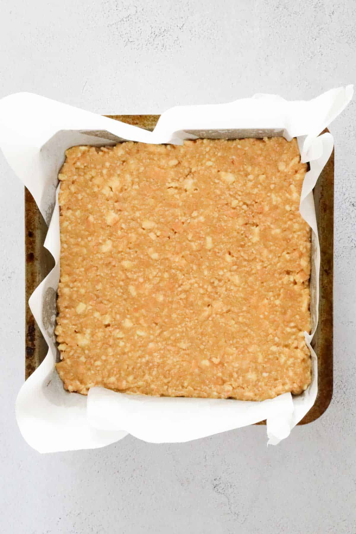 Crushed biscuit base pressed into a lined slice tin.