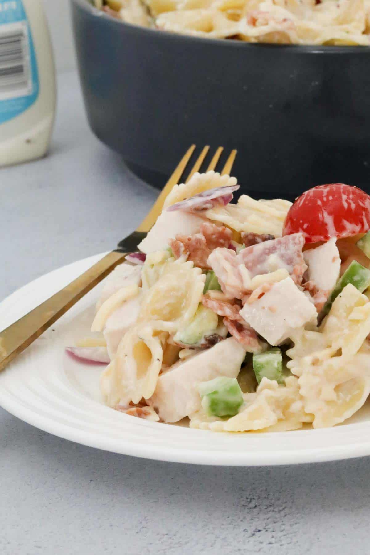 A bowl of chicken pasta salad with a god fork resting on the side.