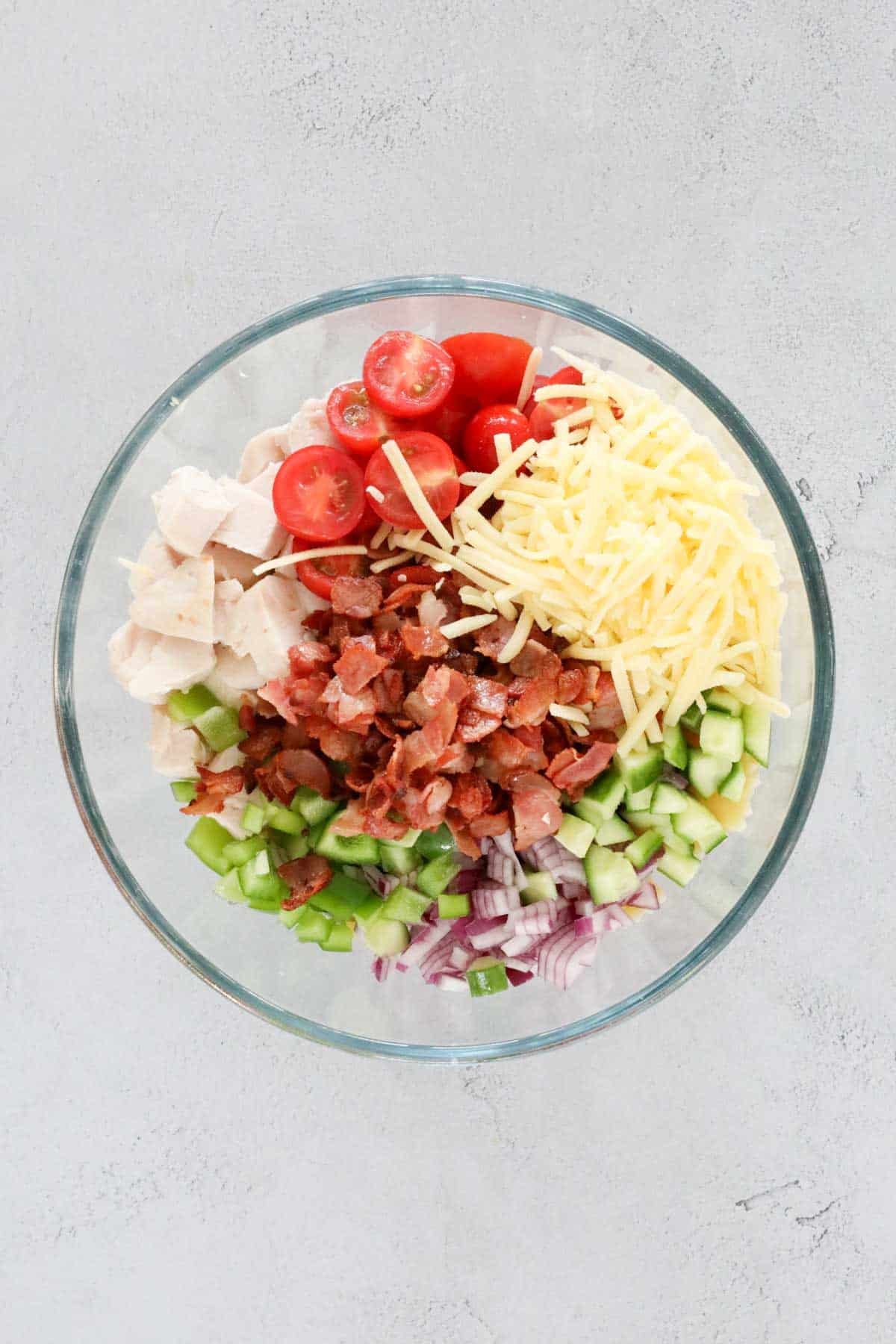 All chicken, bacon and salad ingredients in a large glass bowl.