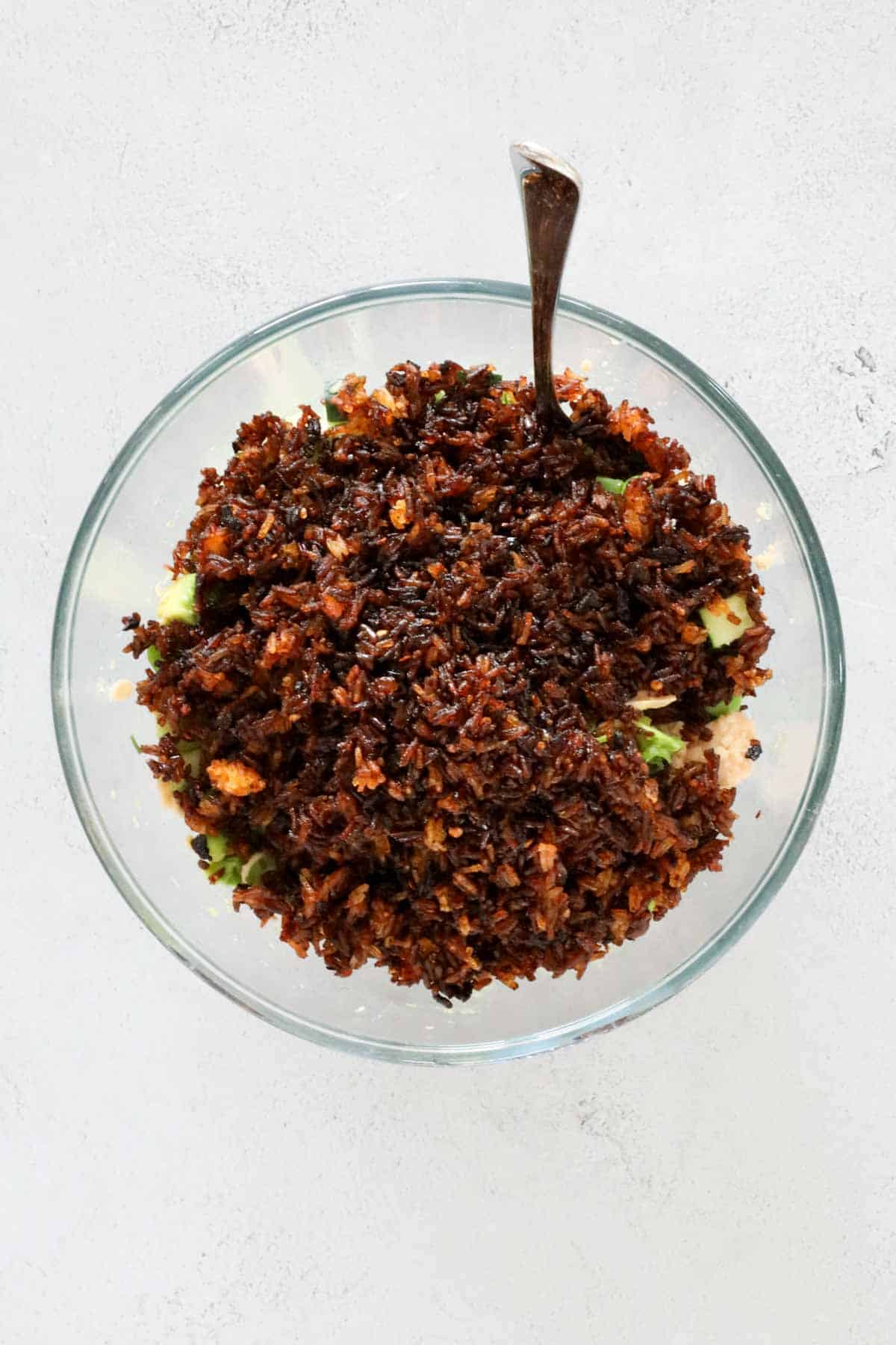 Crispy rice on top of salad ingredients in a bowl.