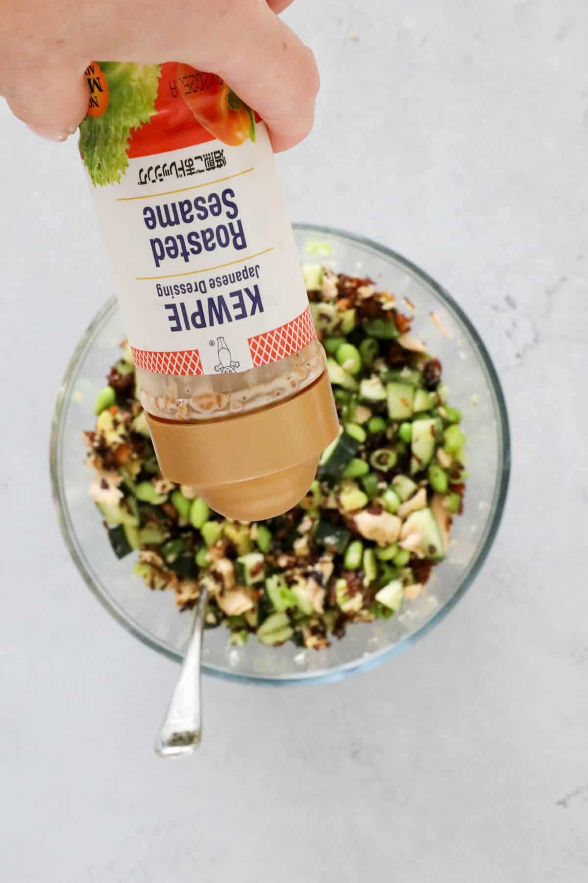 Kewpie roasted sesame dressing being poured onto a bowl of salad.