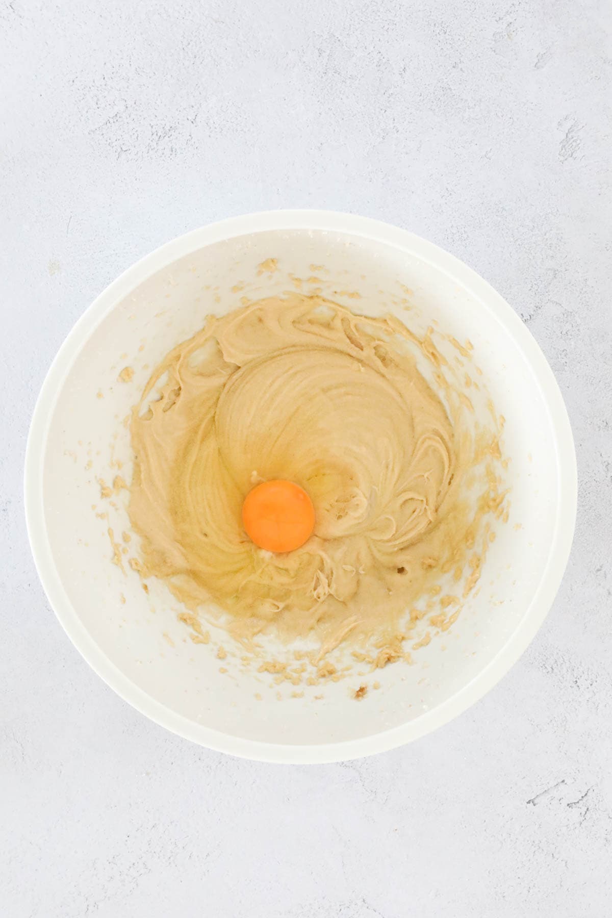 An egg added to mixing bowl of muffin mixture.