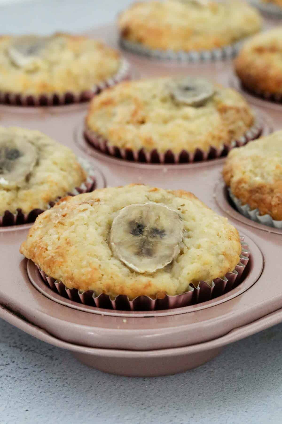 Yoghurt and banana muffins in cases in a muffin baking tray.