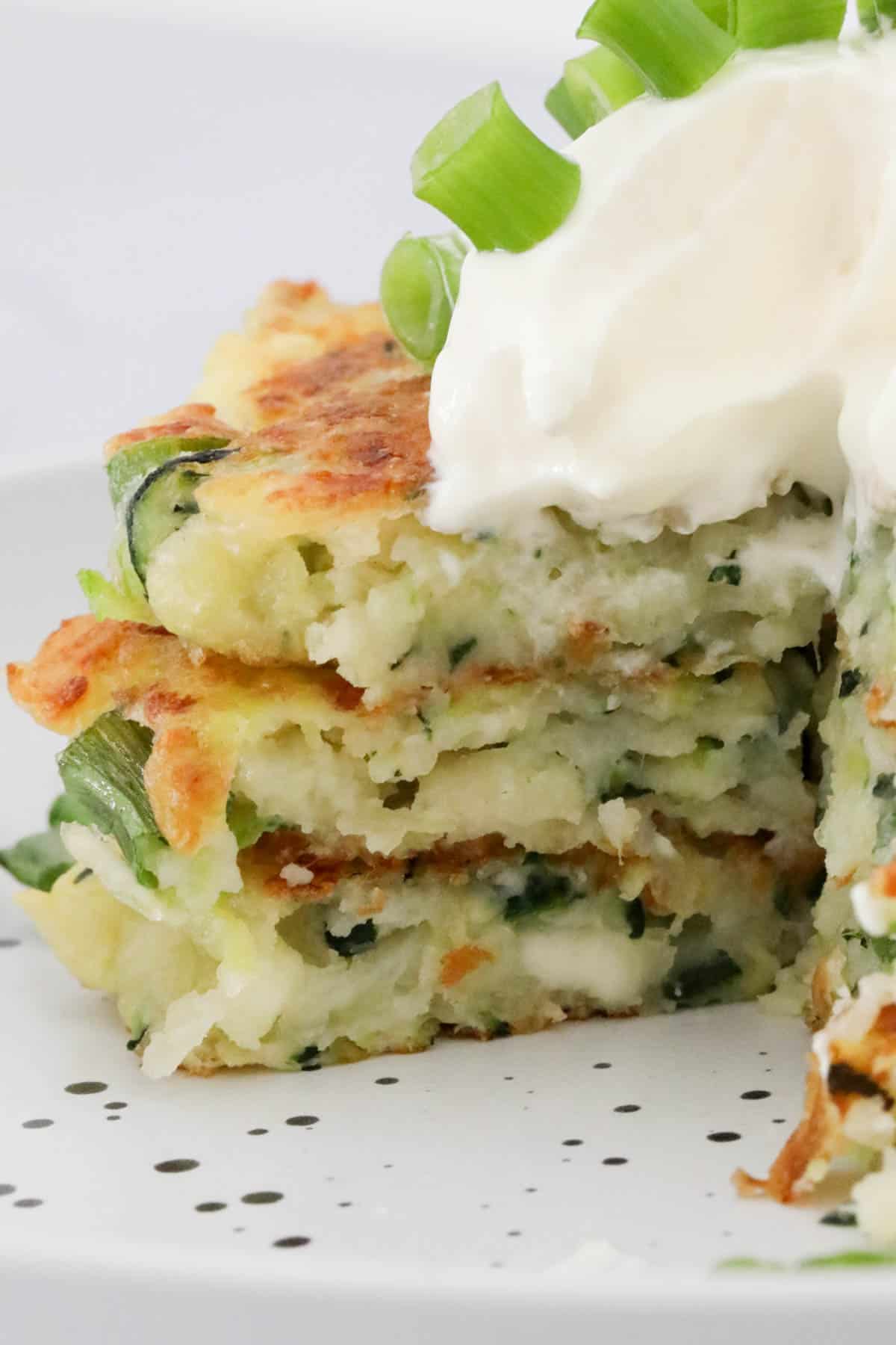 A stack of halloumi and zucchini fritters cut through to show texture inside.