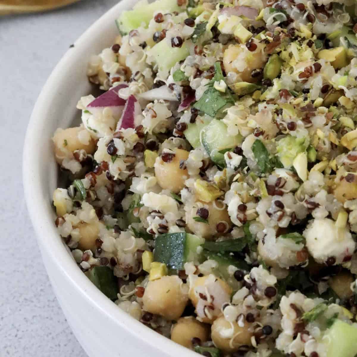 A bowl of chickpeas, quinoa, cucumber and red onion.