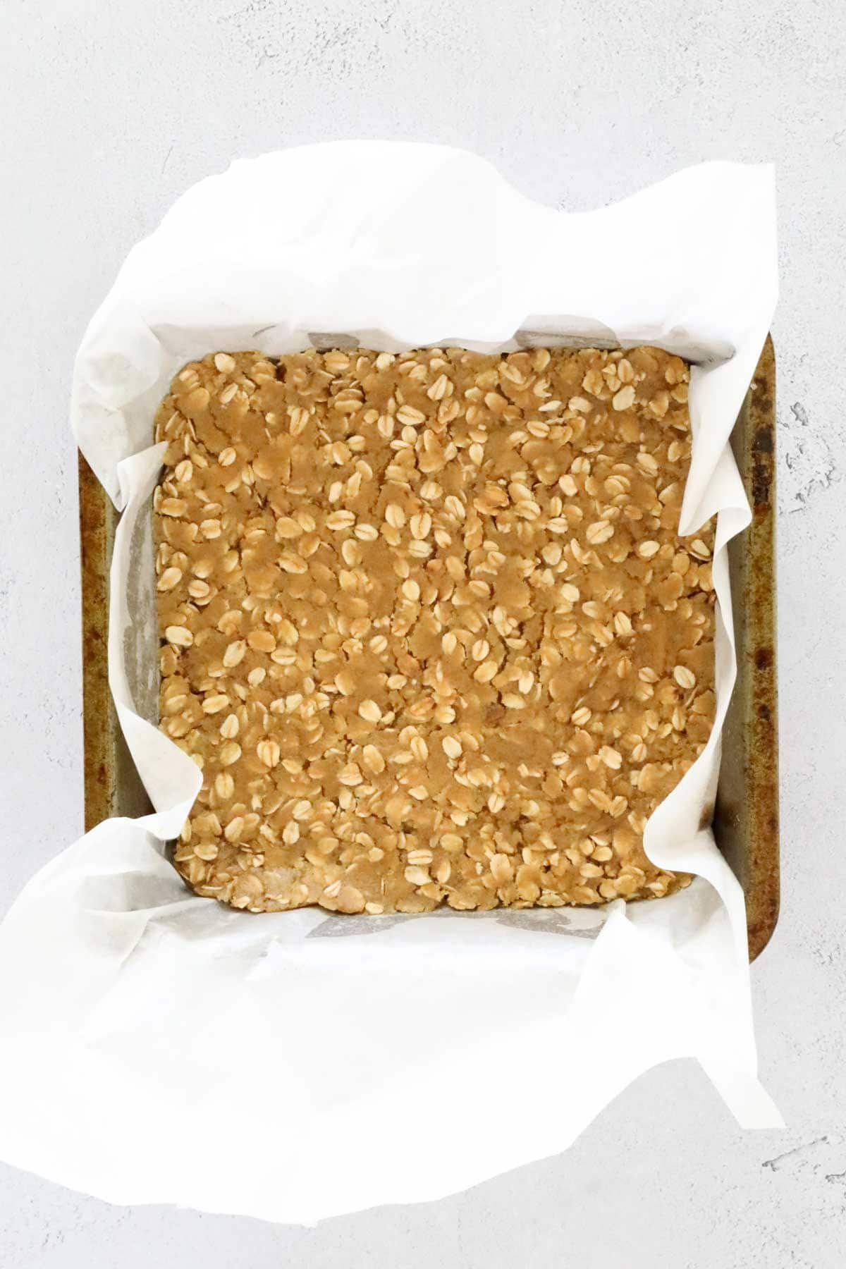 Oat mixture pressed into a baking tin.