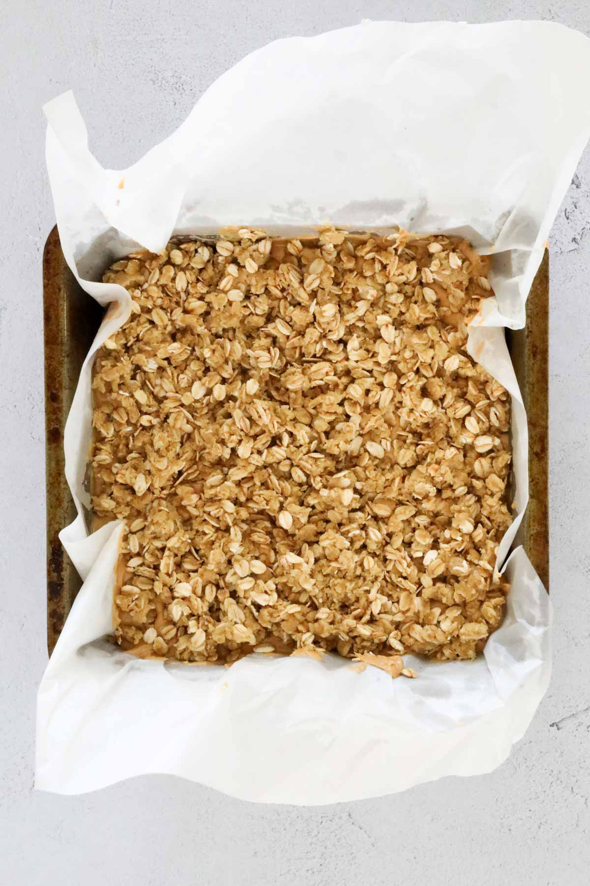 A square baking tin with crumble on top.