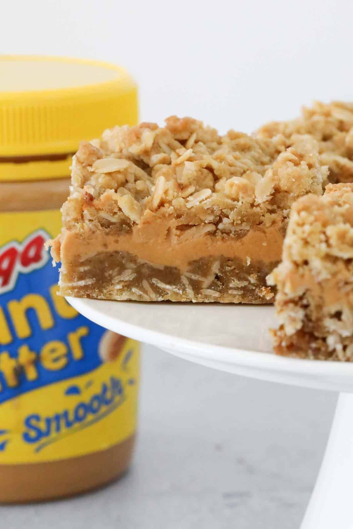 A piece of peanut butter slice with a crunchy oat topping.