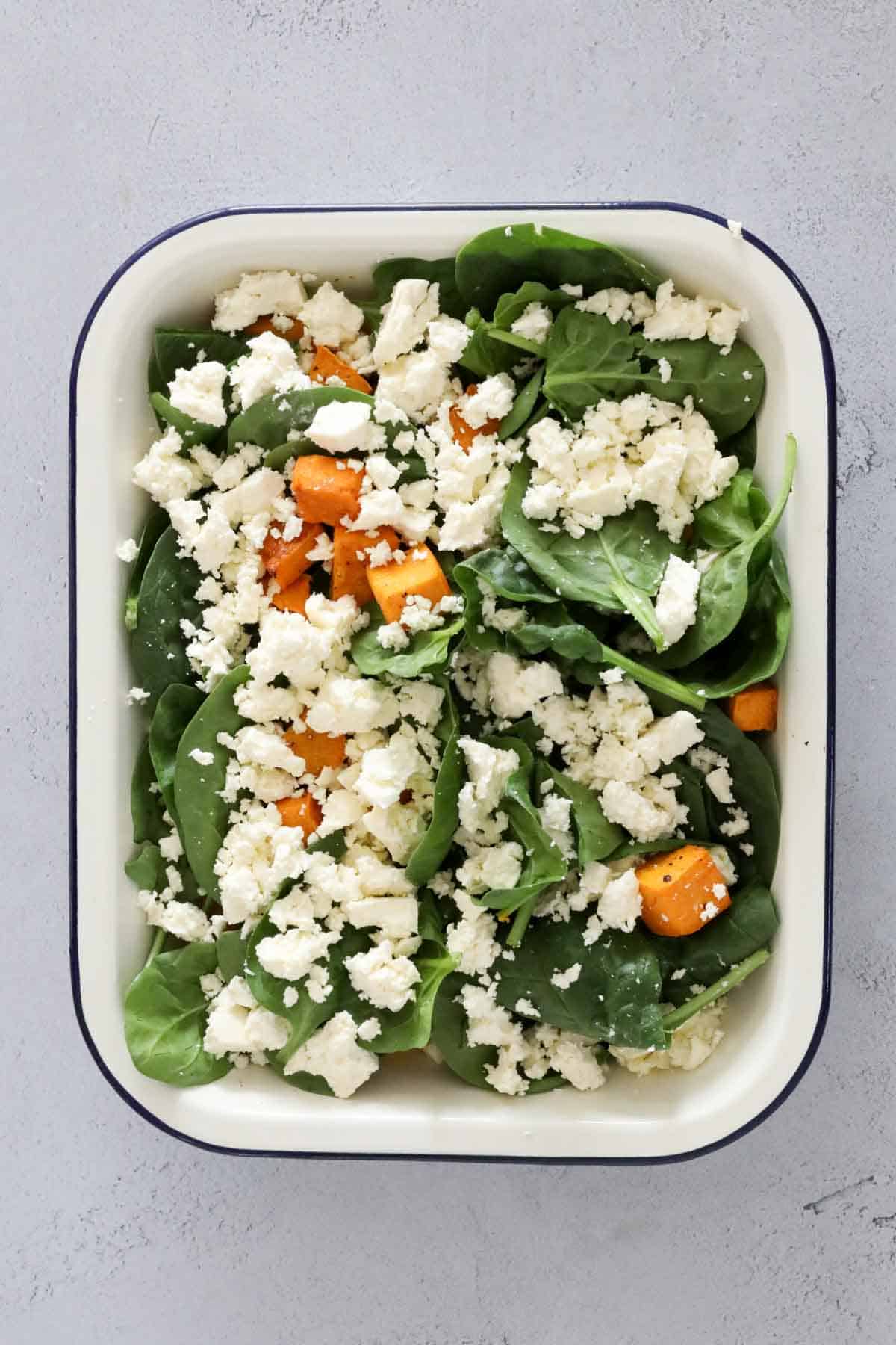 Roasted pumokin, spinach and feta in a baking dish.