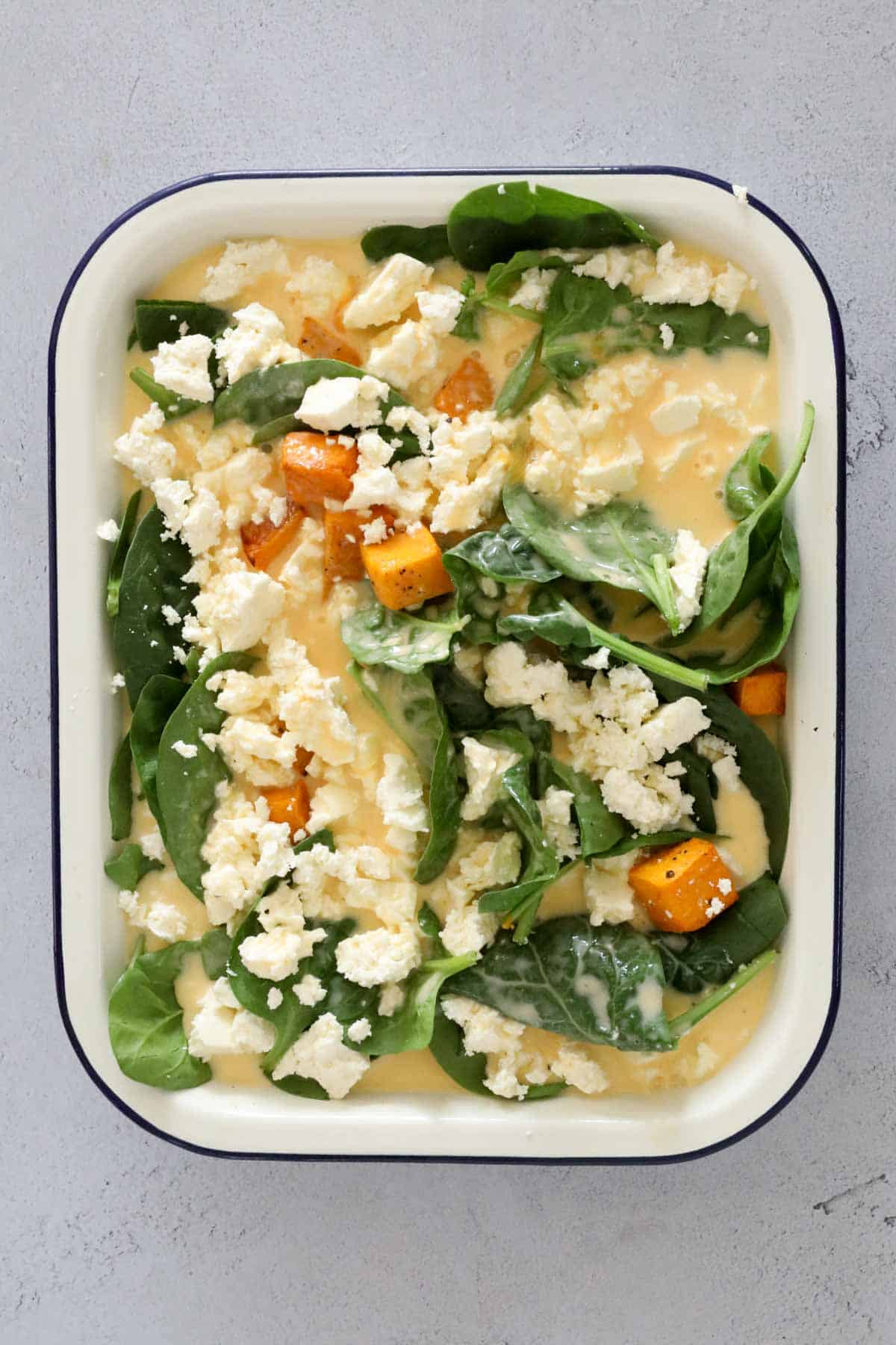 Eggs and cream poured over pumpkin, spinach and feta.