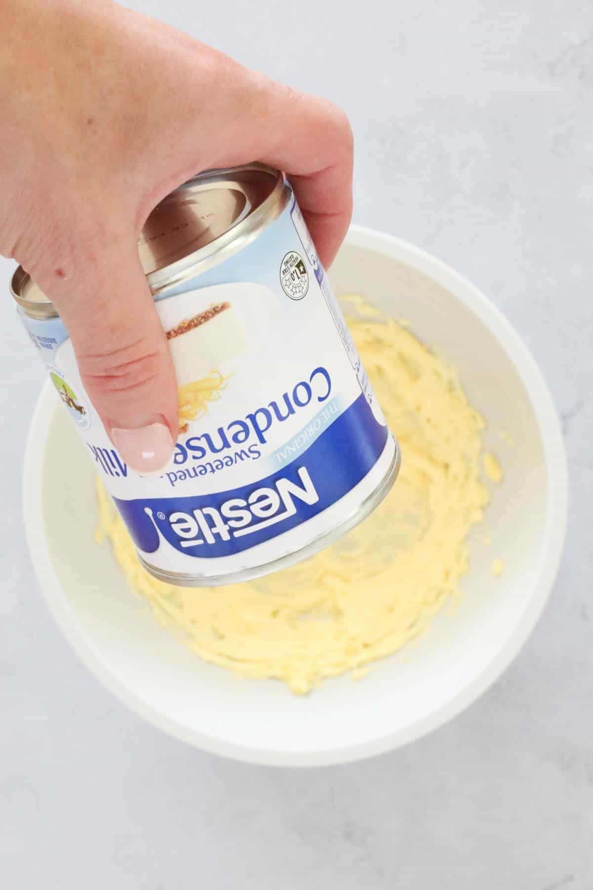 Sweetened condensed milk being poured into a bowl.