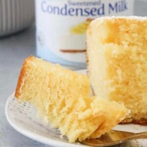 A piece of half eaten cake in front of a can of sweetened condensed milk.