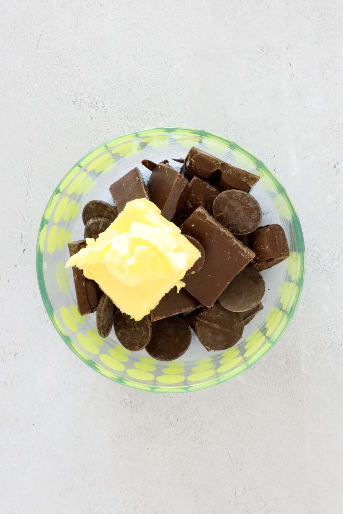 Cunks of dark chocolate and butter placed in a microwave bowl.