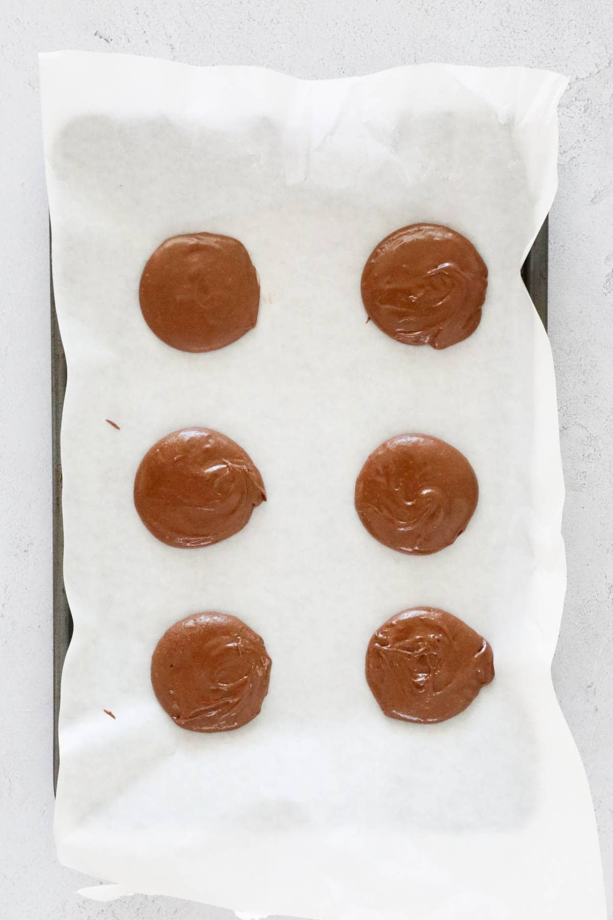 Spoonfuls of mixture on a paper lined baking tray.