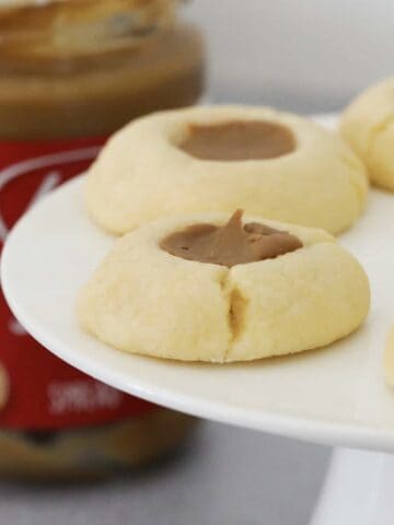 Biscoff filled cookies on a cake stand in front of a jar of Biscoff.