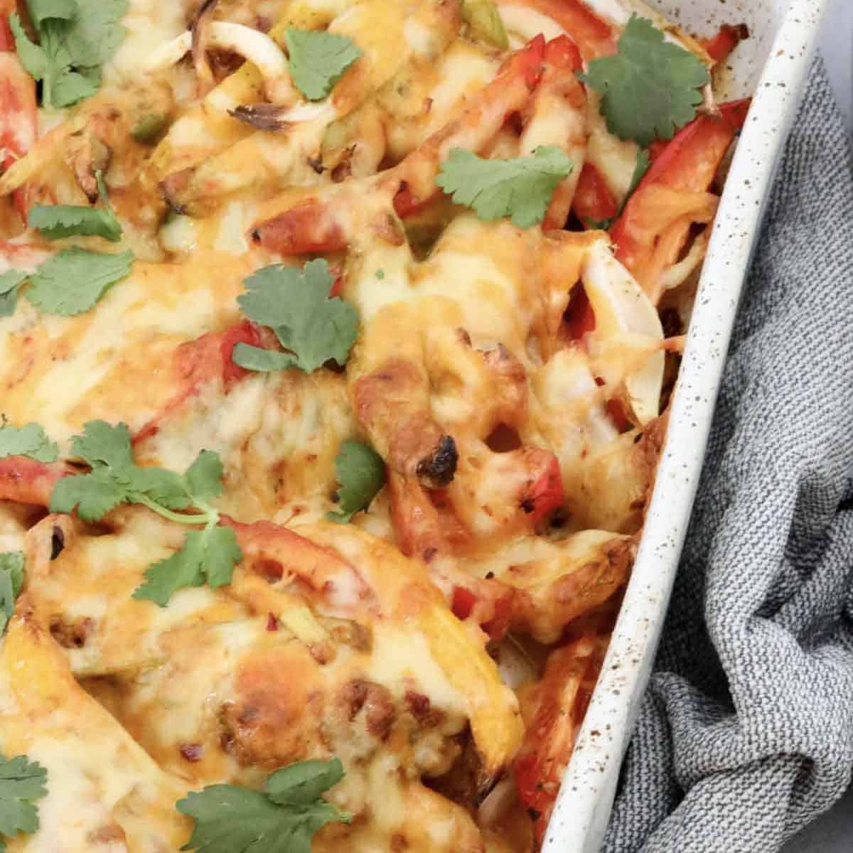 Freshly baked chicken fajita casserole topped with golden melted cheese and garnished with fresh coriander.