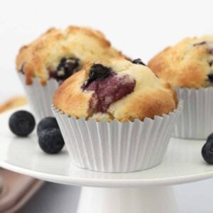Blueberry muffins on a white cake stand.