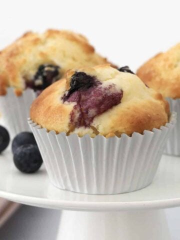 Blueberry muffins on a white cake stand.