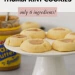 Peanut Butter Thumbprint Cookies on a white cake stand.