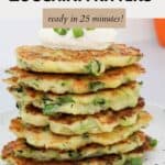 A stack of halloumi and zucchini fritters with sour cream on top and sprinkled with chopped spring onions.