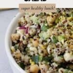 A white bowl filled with a fresh salad full of quinoa, salad vegetables and seeds, tossed in a light dressing.