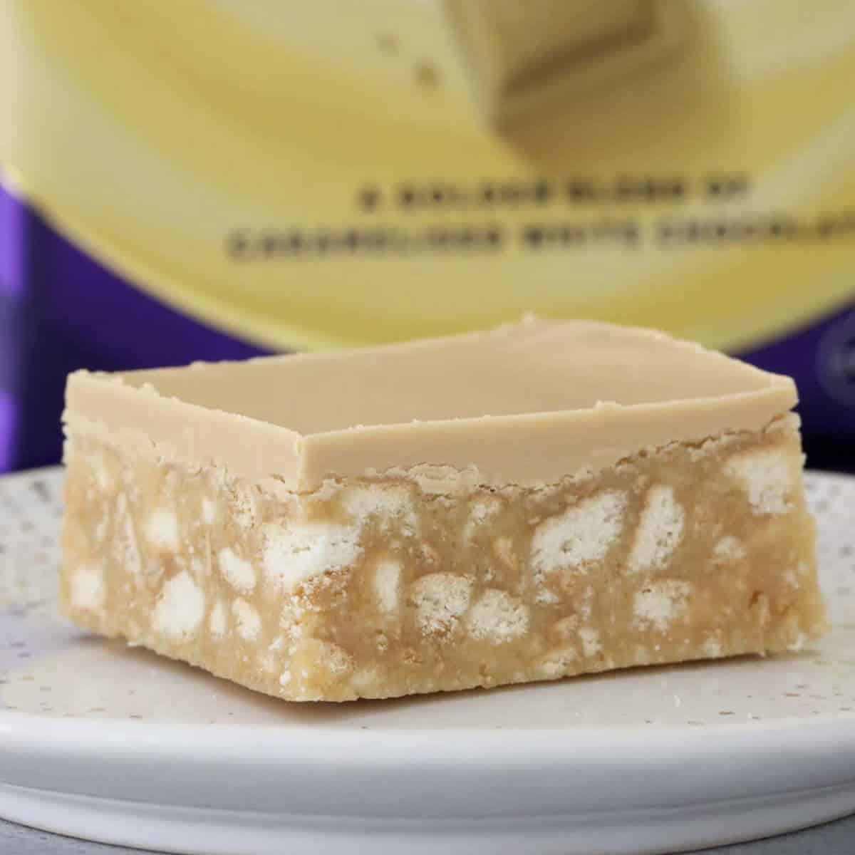 A piece of no bake caramel hedgehog slice in front of a block of caramel chocolate.