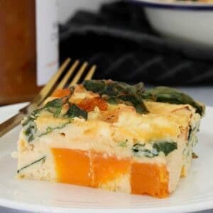A piece of frittata with pumpkin, spinach and feta on a white plate.